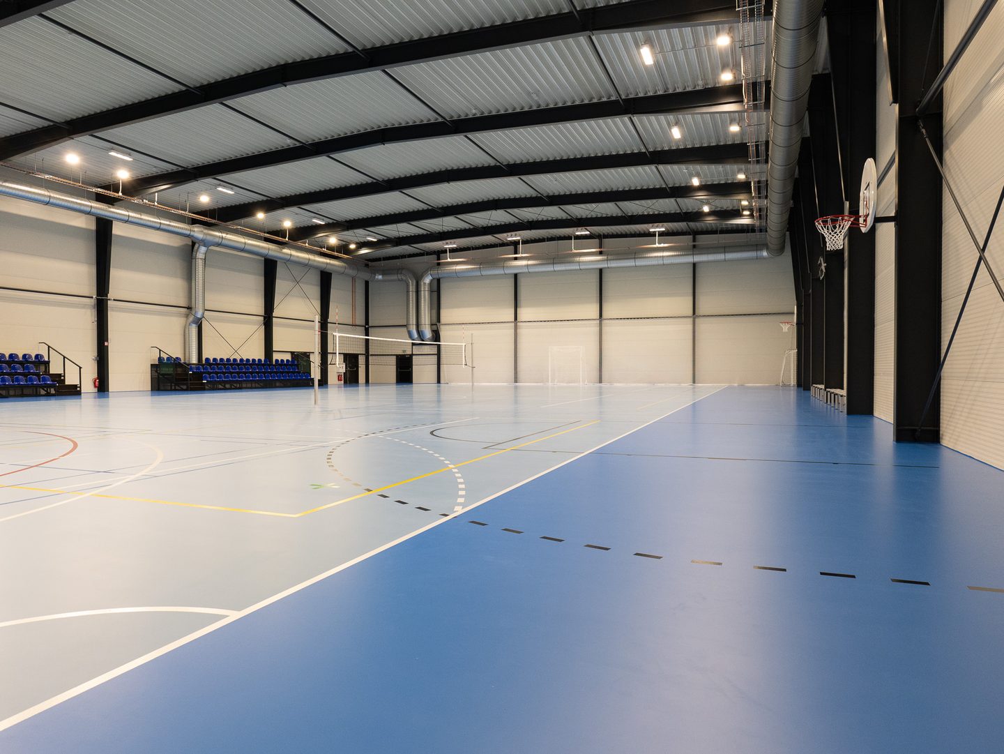 Hrací plocha se sklopným basketbalovým košem u stěny.